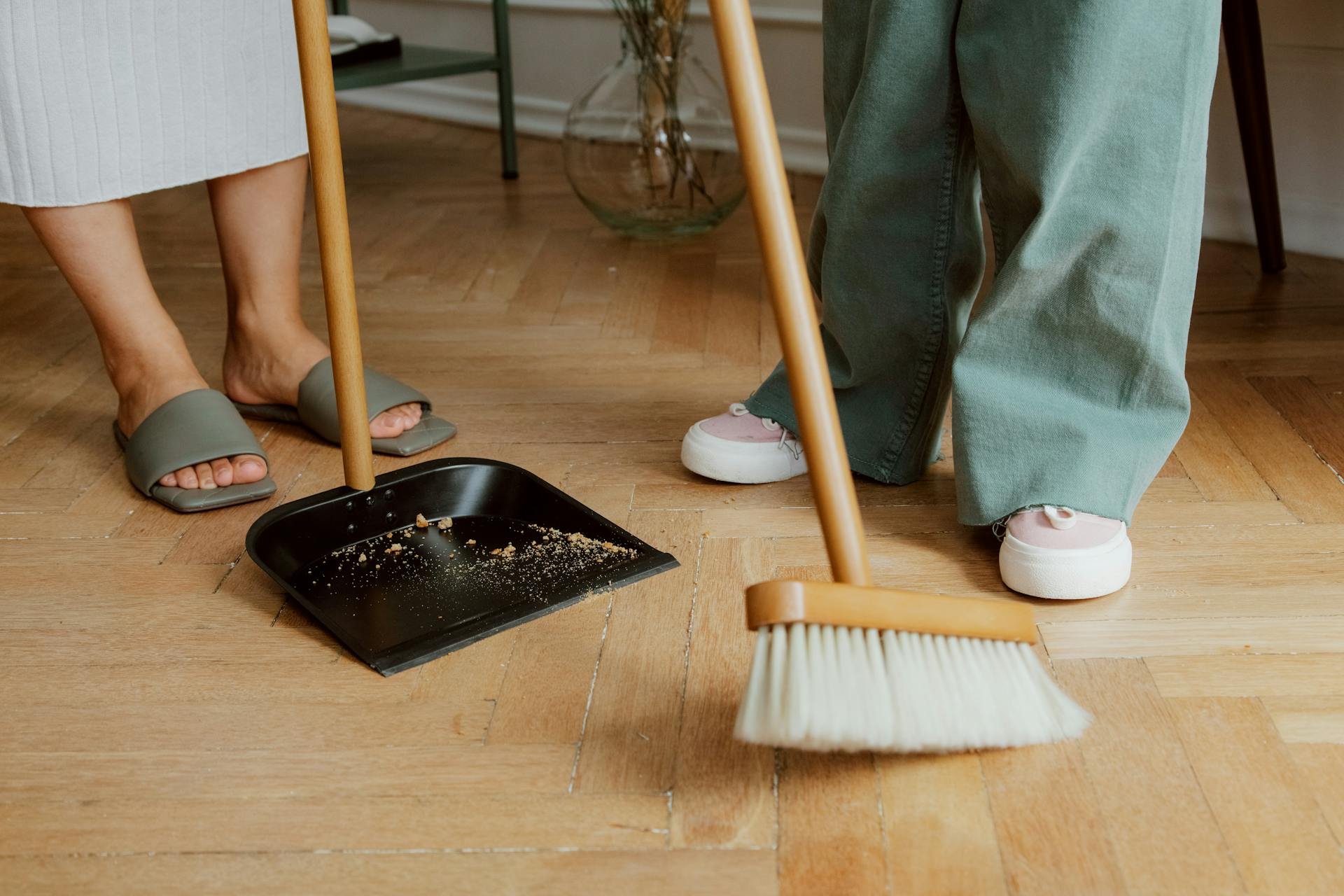 Two people sweeping the floor