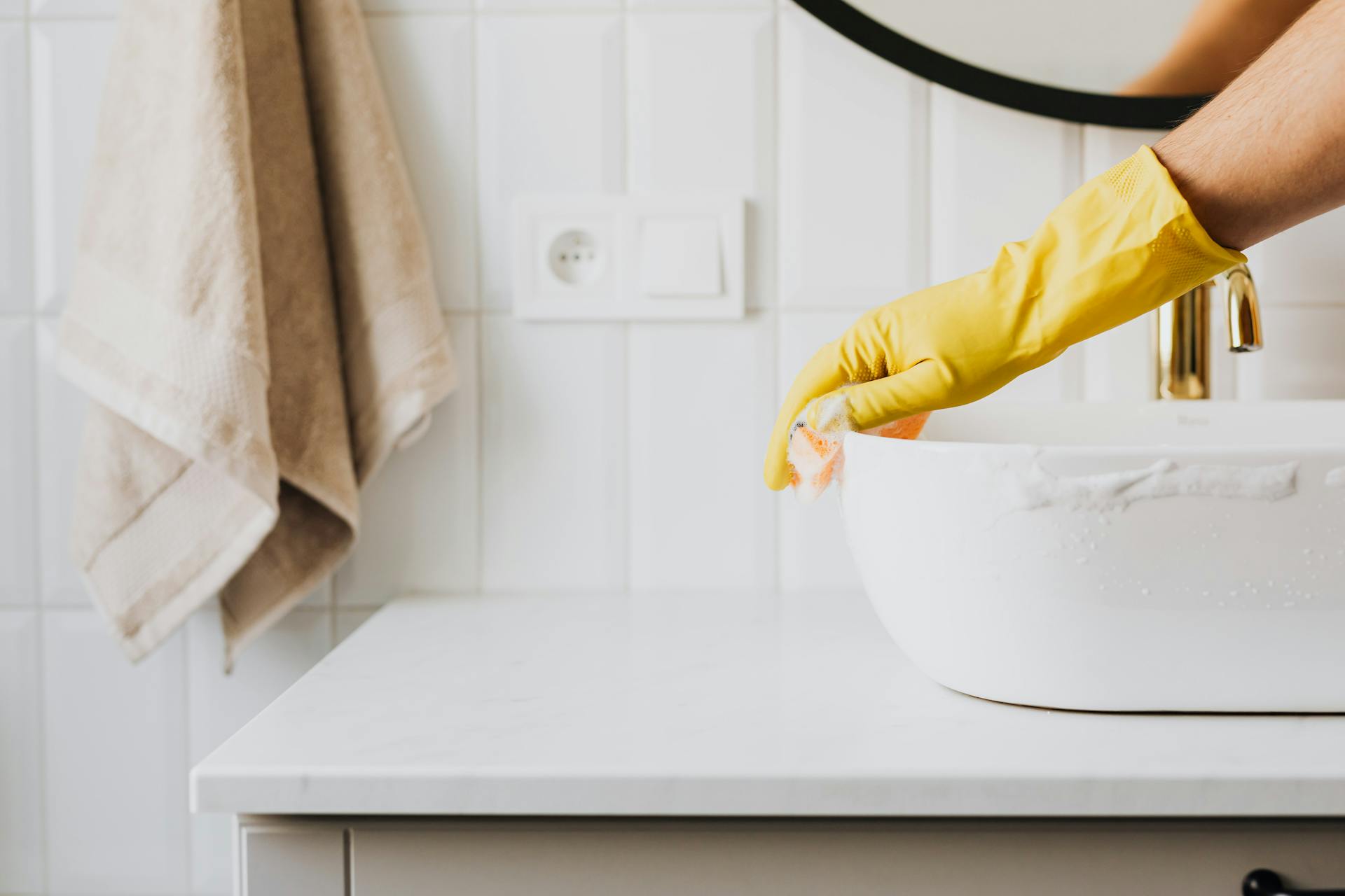 Person cleaning sink in bathroom